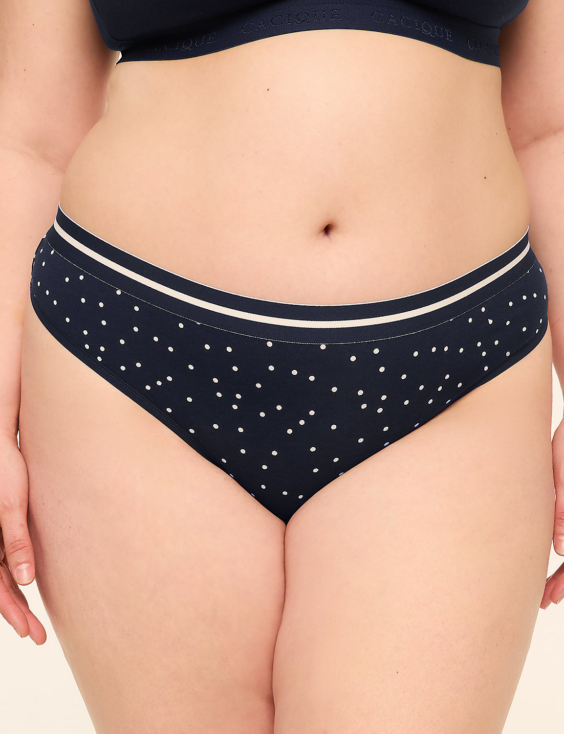 A close-up of a person's torso in navy blue polka dot underwear with a white stripe at the waistband, set against a plain, light background. Product Image 1