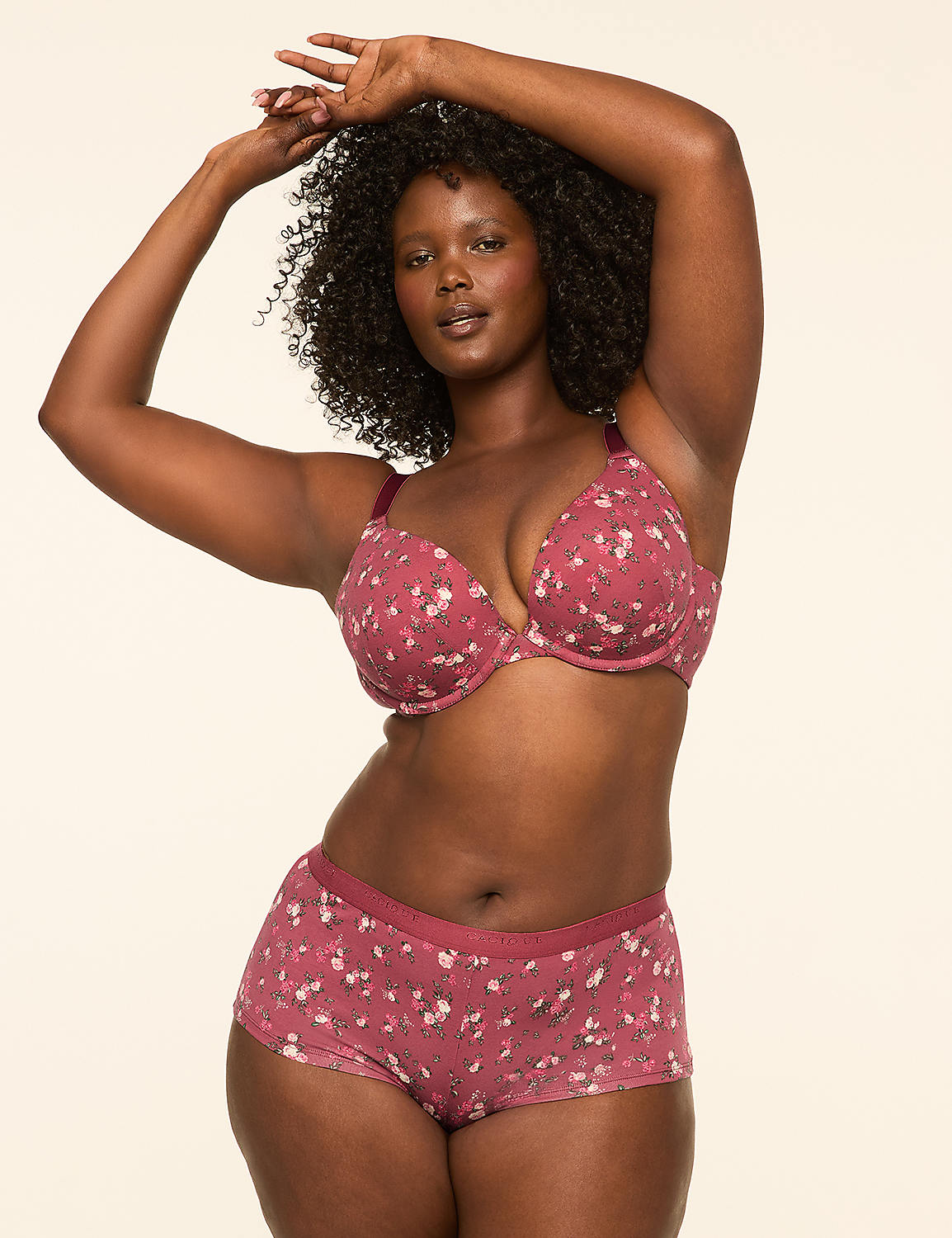 A woman with dark curly hair poses in a floral print bra and matching shorts against a plain, light-colored background. Product Image 4