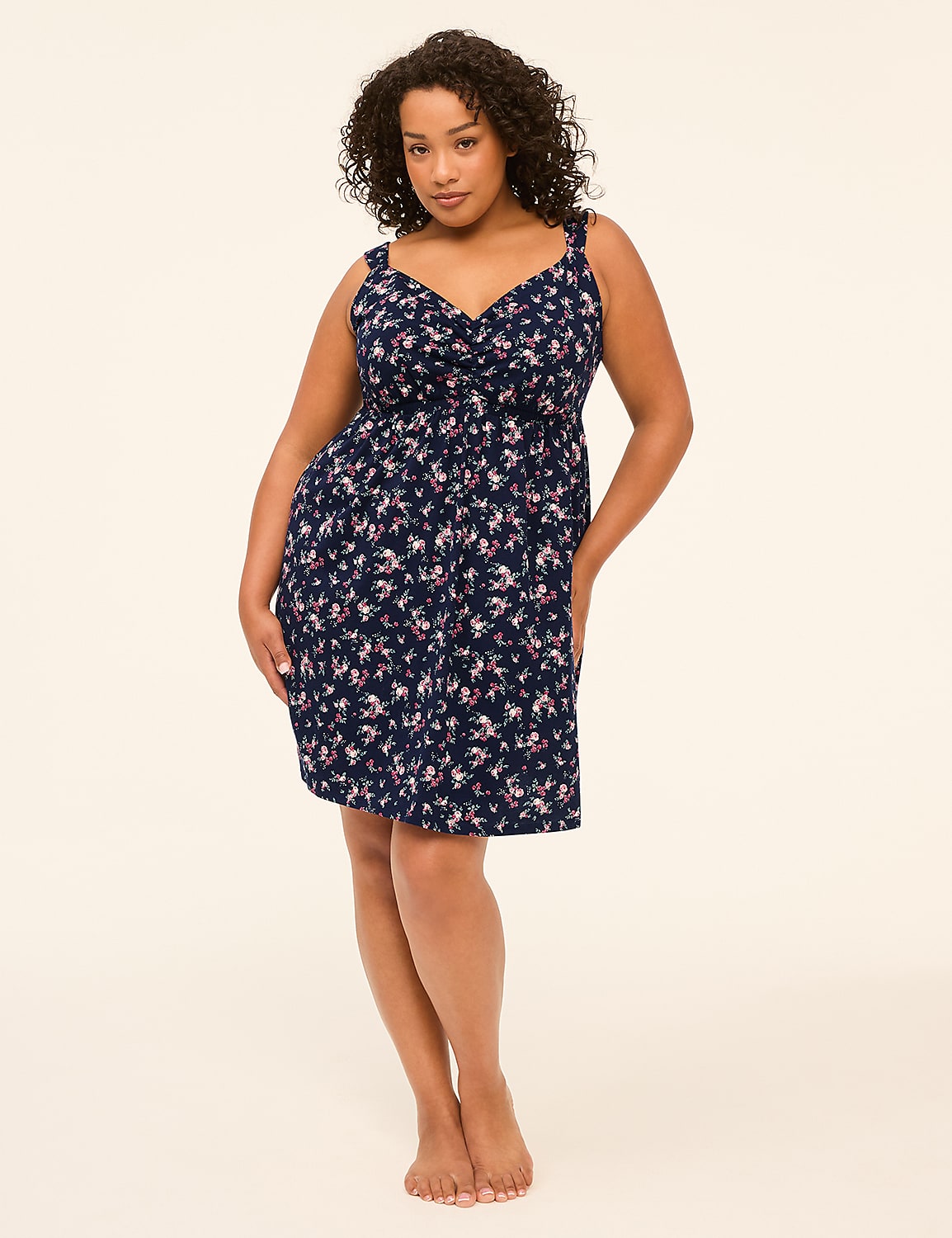 A woman in a floral dress stands against a plain, light-colored background. Product Image 1
