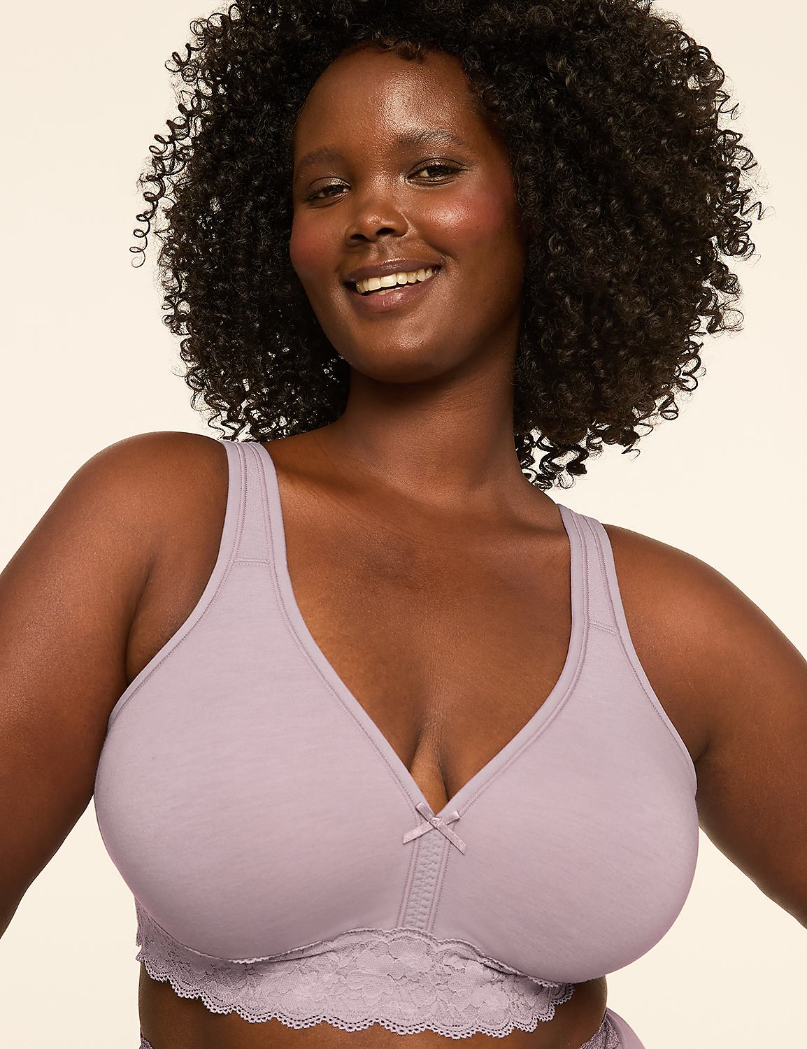 A smiling woman with dark curly hair wears a light purple bra with lace trim against a plain, light-colored background. Product Image 1