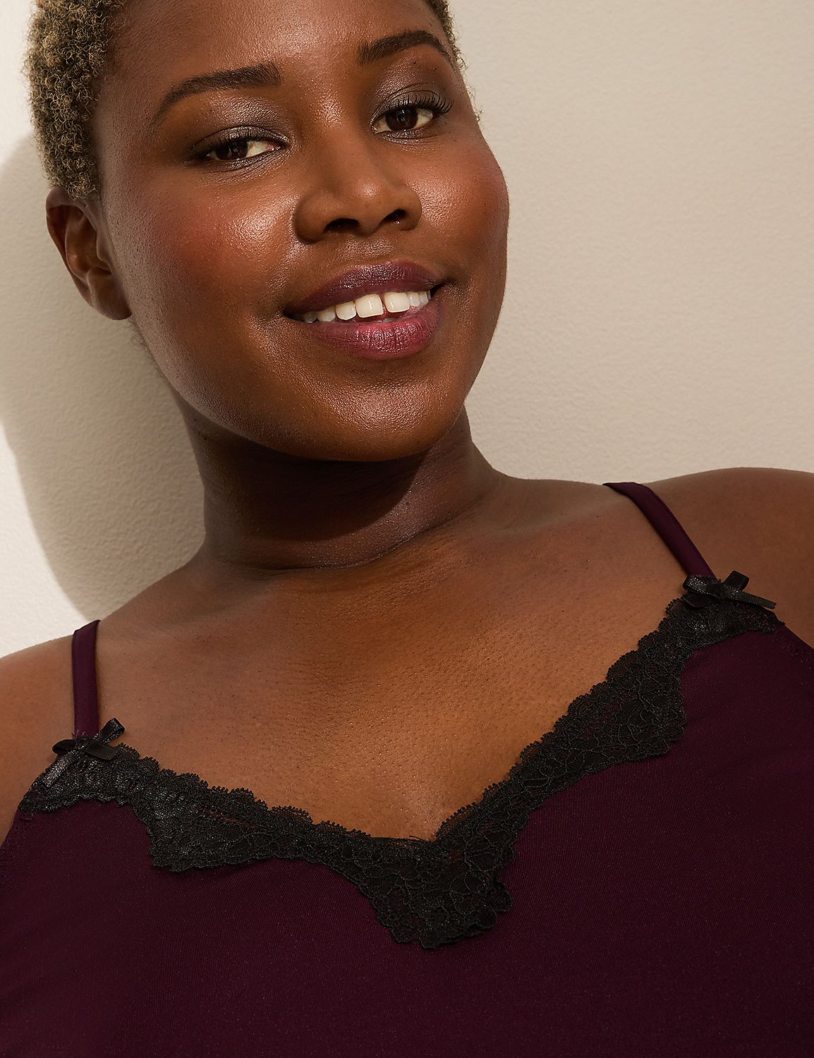 A smiling woman with short hair wears a burgundy camisole with black lace trim, set against a plain, light-colored background. Product Image 4