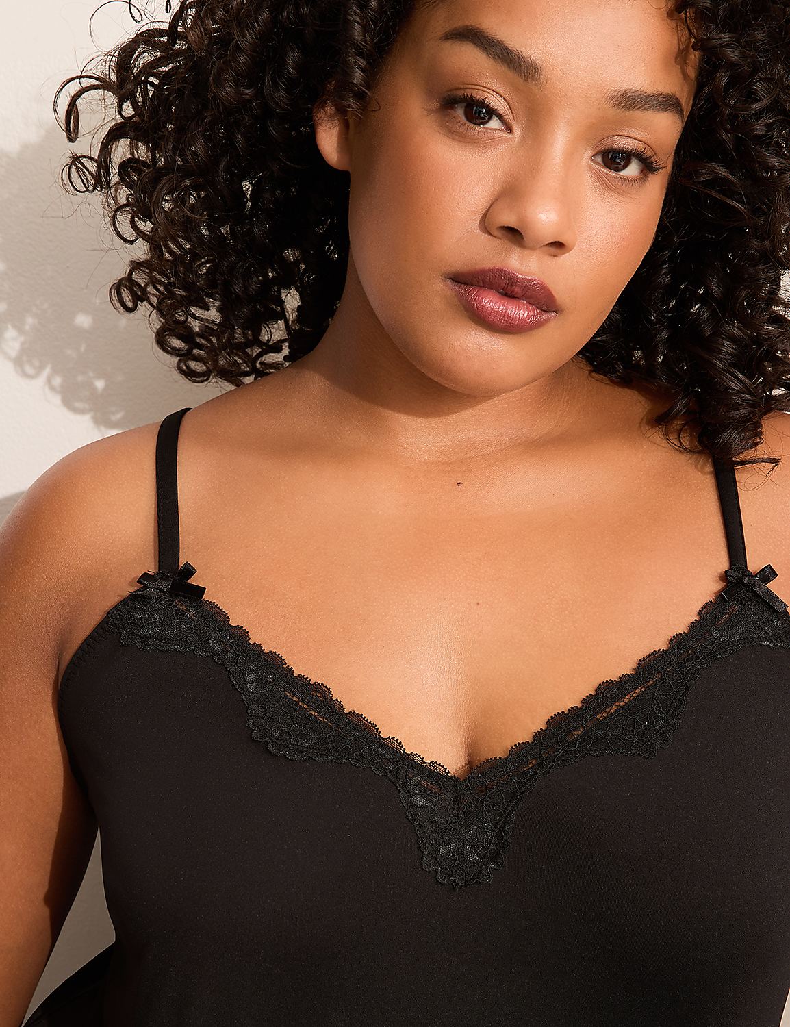 A woman with curly dark hair wears a black camisole with lace trim in the foreground, against a plain white background. Product Image 3