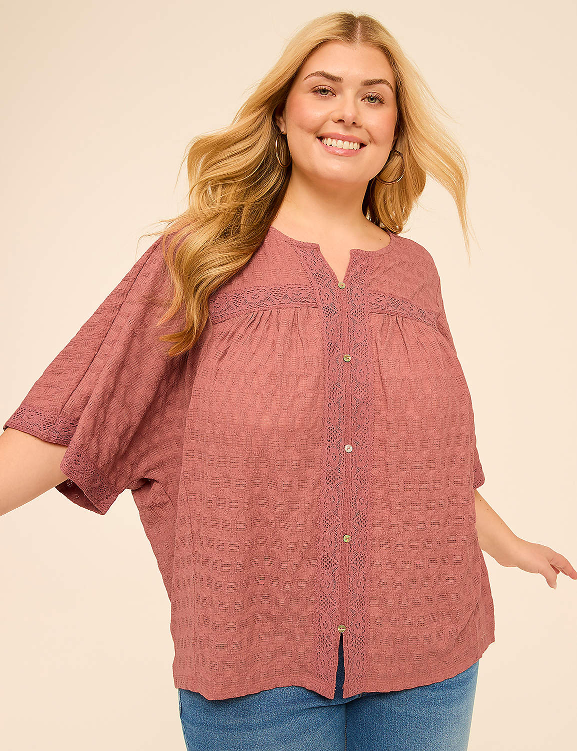 A smiling woman with blonde hair and a pink blouse stands against a plain, light-colored background. Product Image 1