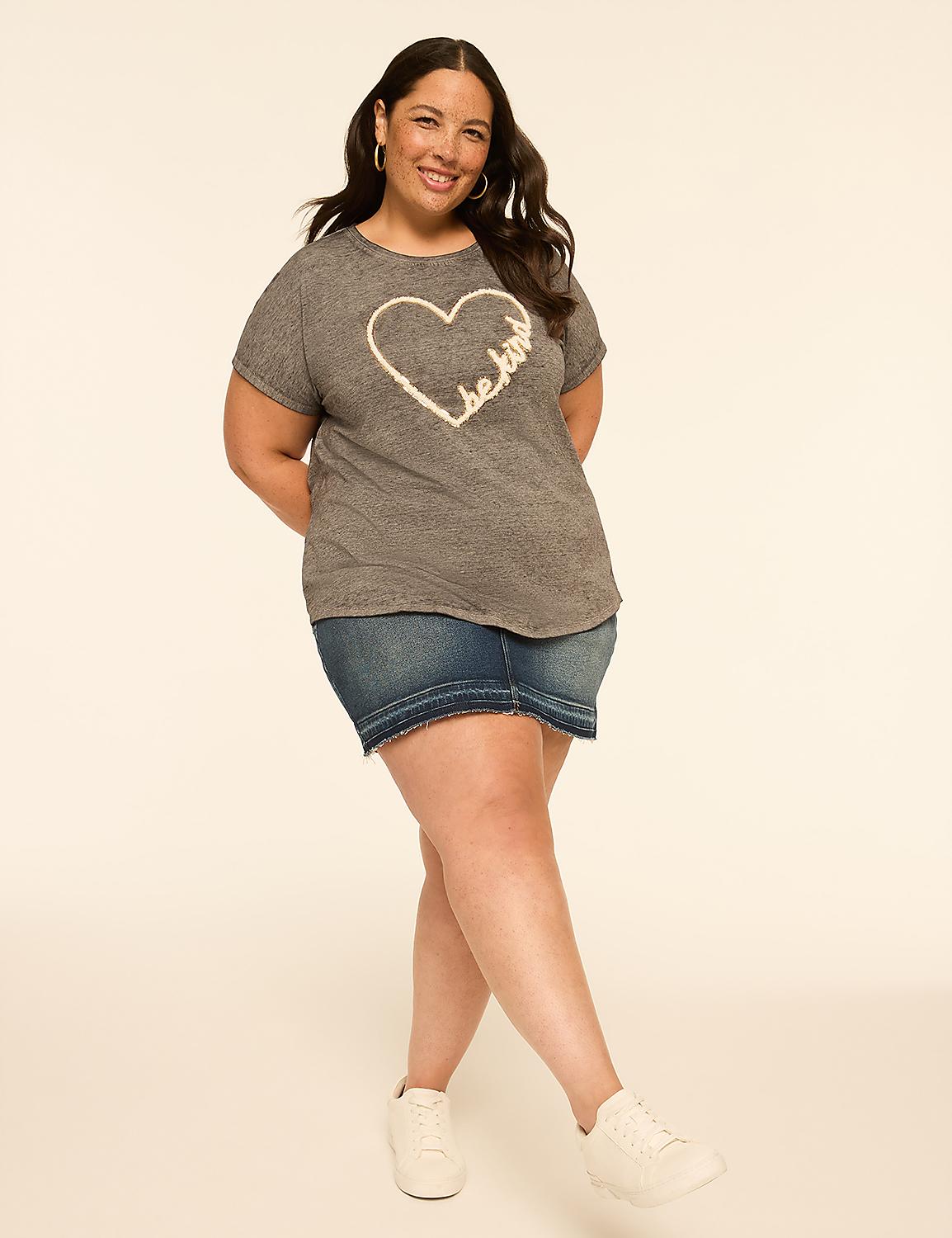 A smiling woman in a grey t-shirt with a heart design and a denim skirt stands against a plain, light-colored background. Product Image 3