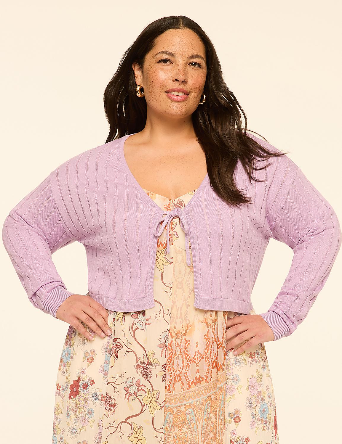 A woman in a floral dress and a lavender cardigan stands against a plain, light-colored background. Product Image 1