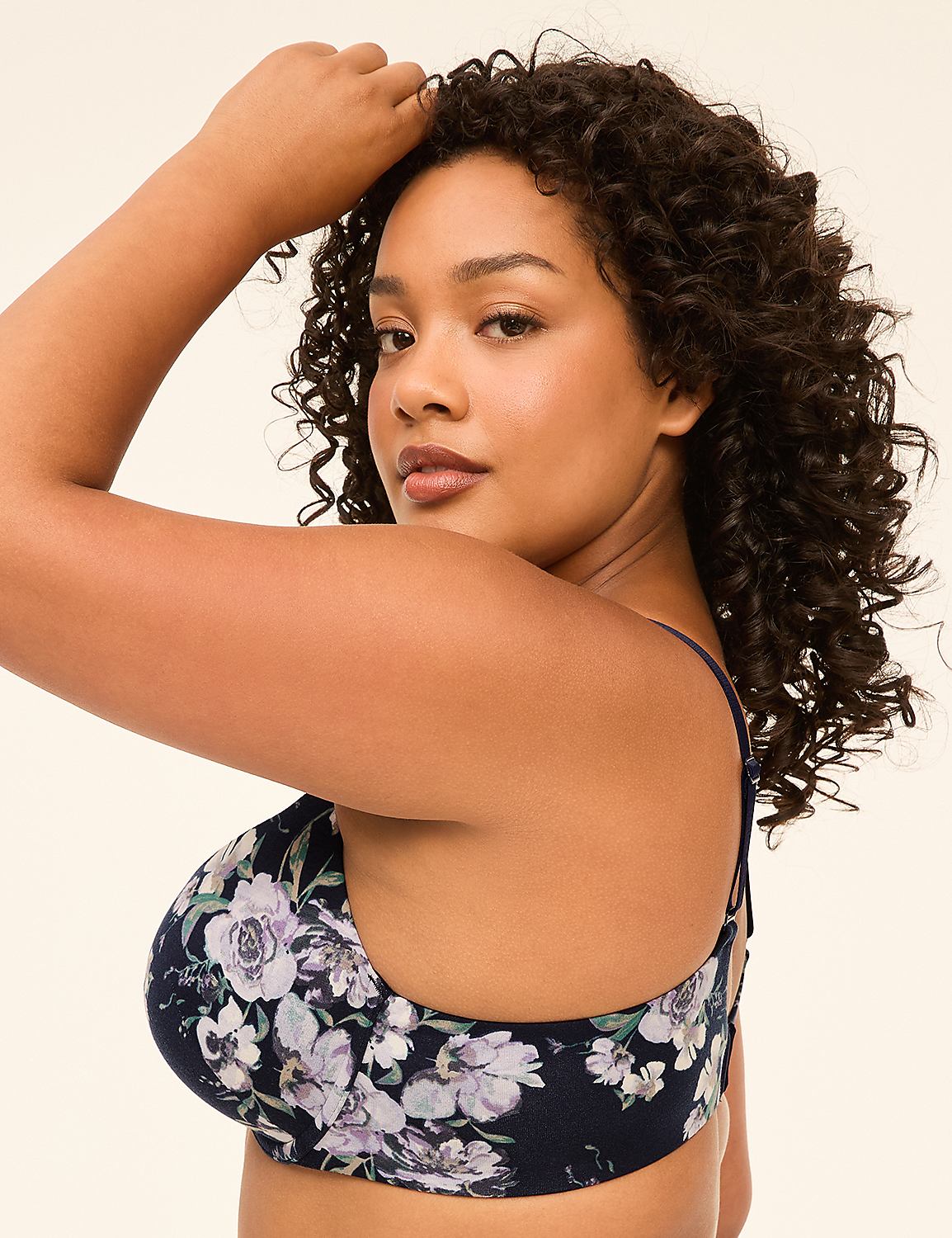 A woman with curly dark hair poses in a floral bra against a plain, light-colored background. Product Image 3