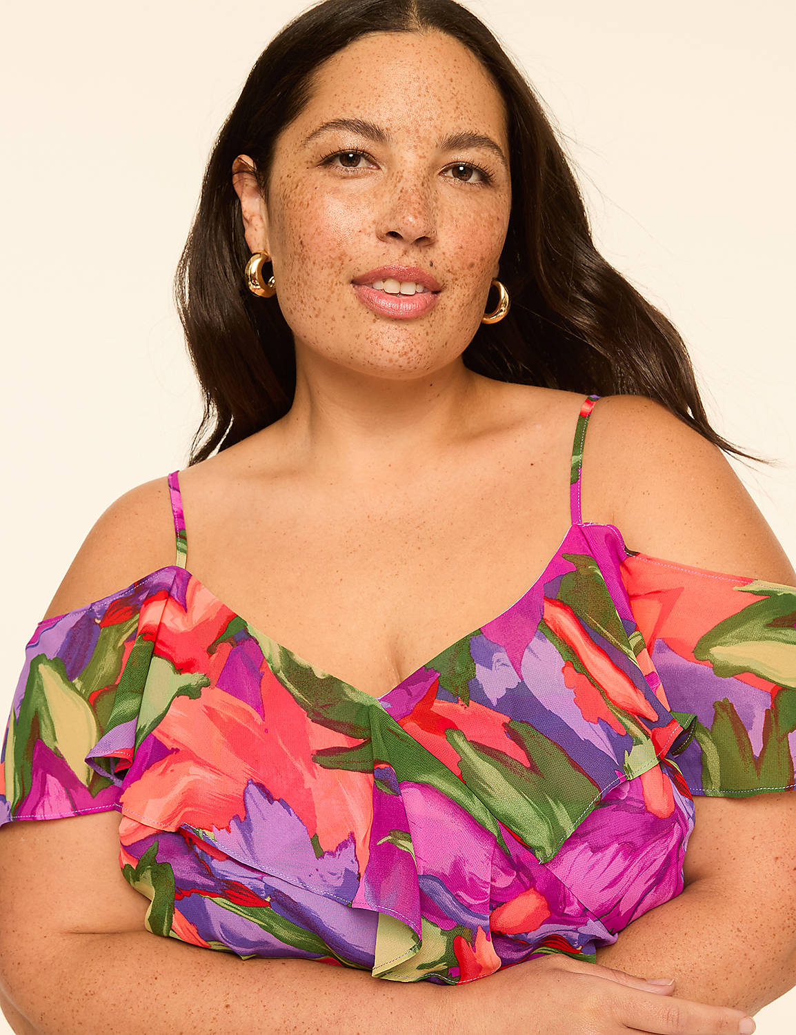 A woman with freckles and gold hoop earrings smiles at the camera, wearing a vibrant floral off-the-shoulder dress against a plain, light-colored background. Product Image 3