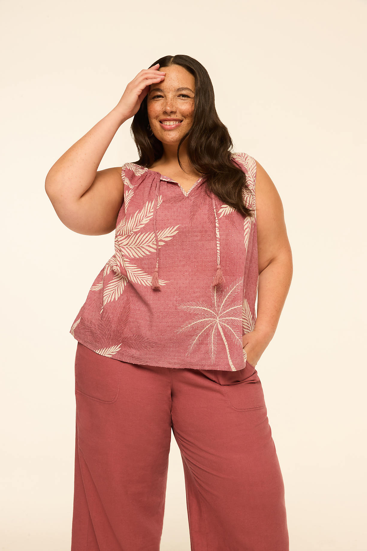 A smiling woman in a patterned top and wide-leg pants stands against a plain, light-colored background. Product Image 8