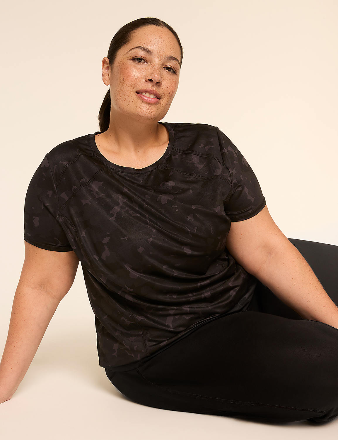 A woman in a black tie-dye t-shirt and black leggings poses against a plain, light-colored background. Product Image 3