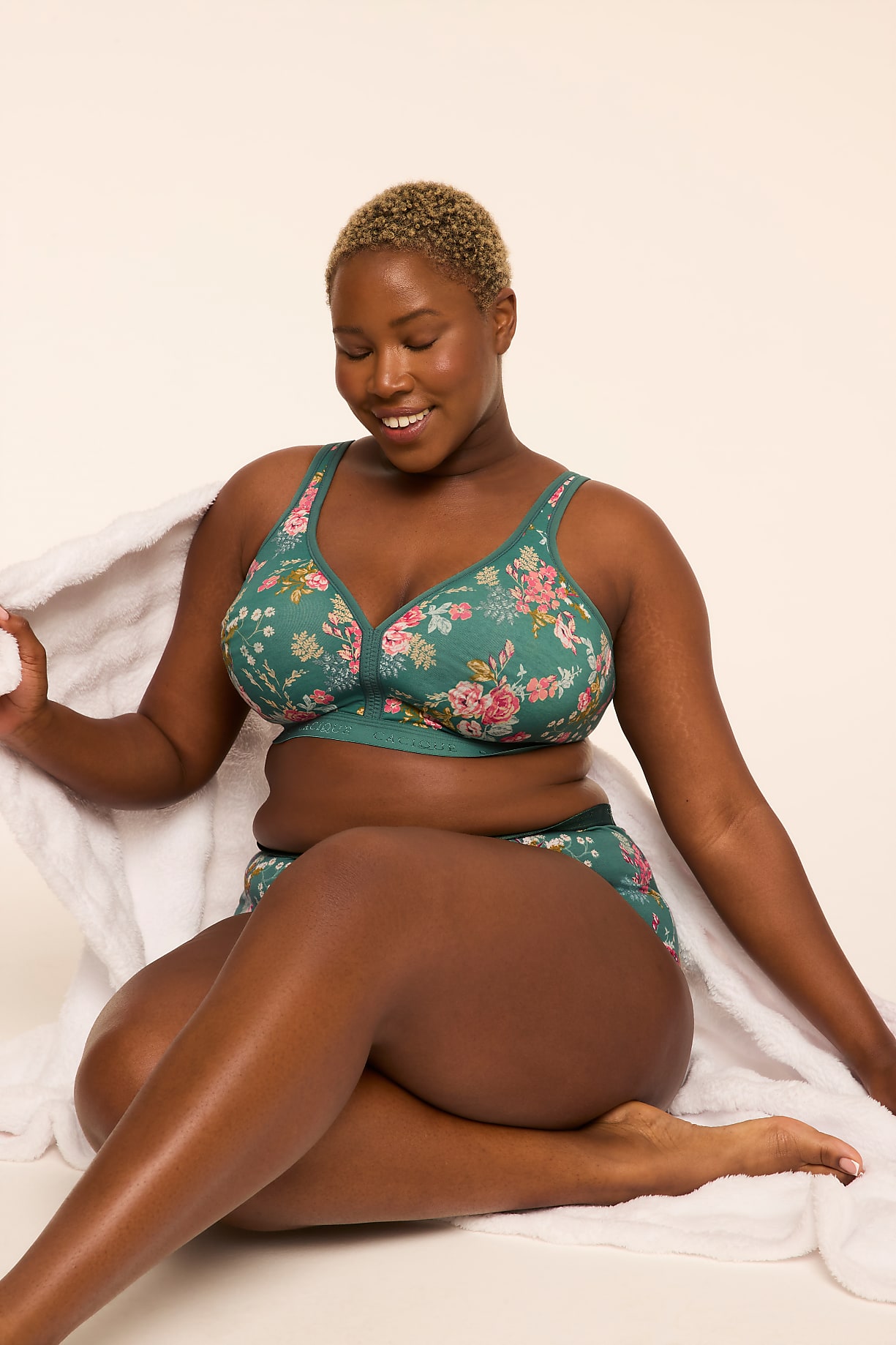 A smiling woman with short blonde hair, wearing a floral bra and underwear, sits draped in a white towel against a plain, light background. Product Image 9