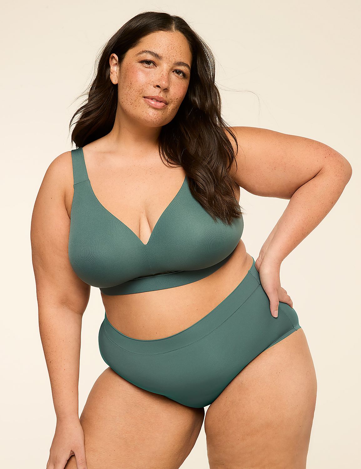 A woman with dark hair and freckles poses in a teal bra and high-waisted underwear against a plain, light background. Product Image 4