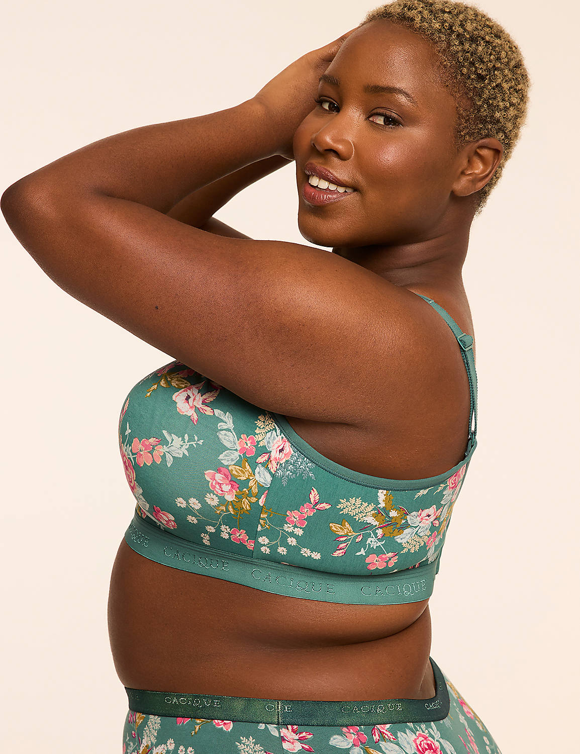 A woman with short, curly hair smiles as she poses in a floral-patterned bra and matching underwear against a plain, light-colored background. Product Image 3