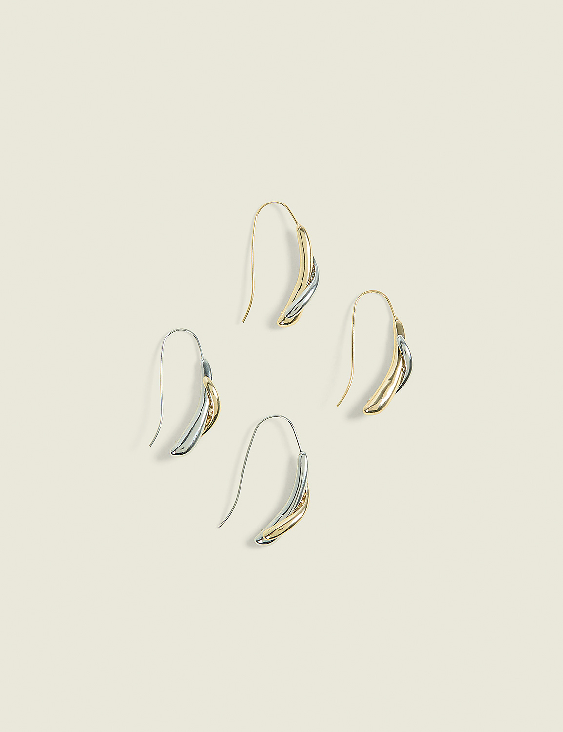 Four elegant, two-toned earrings with curved, layered designs are arranged in a diamond pattern against a soft, cream-colored background. Product Image 1