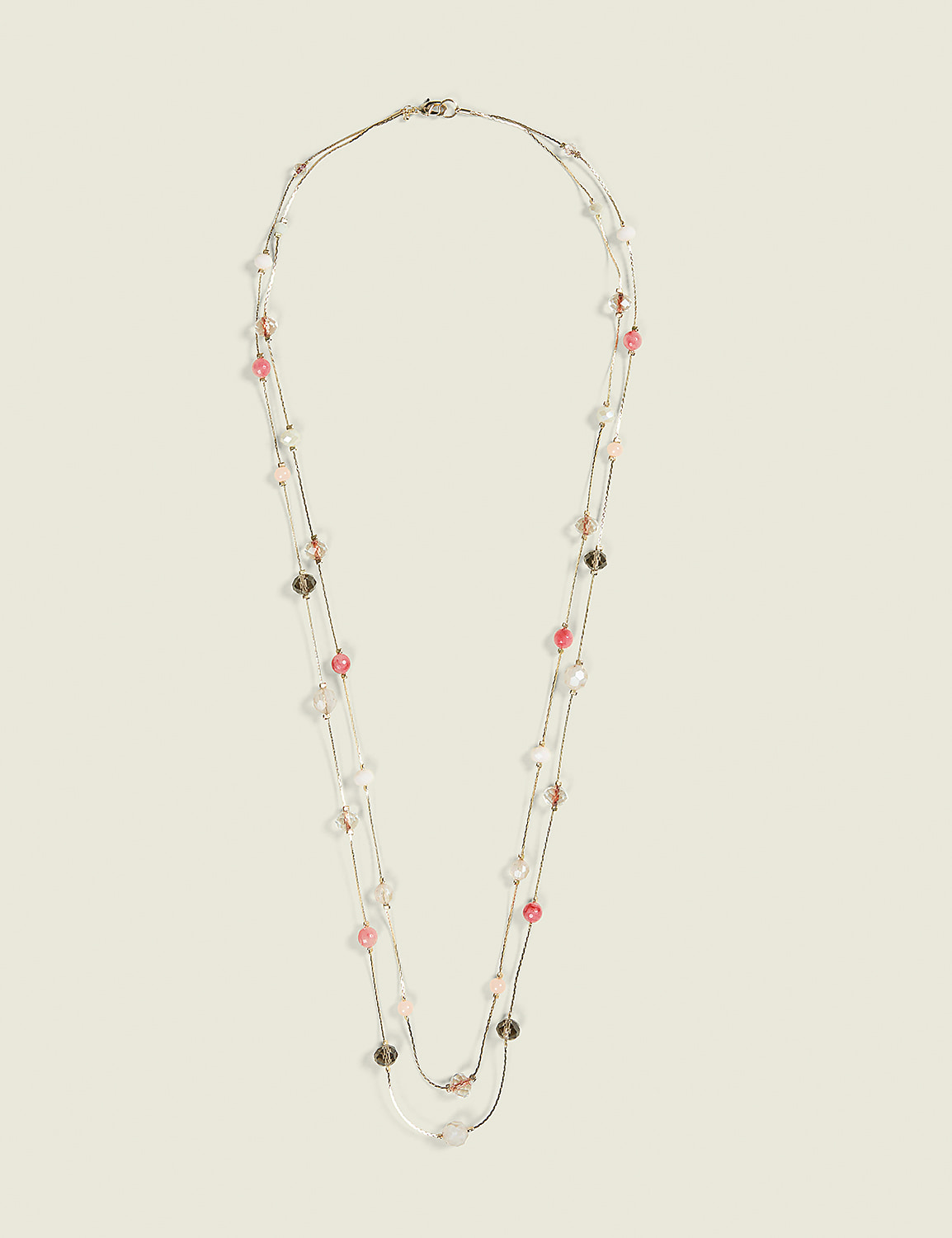 A delicate, multi-strand necklace with pink and clear beads is displayed against a plain, light beige background. Product Image 1