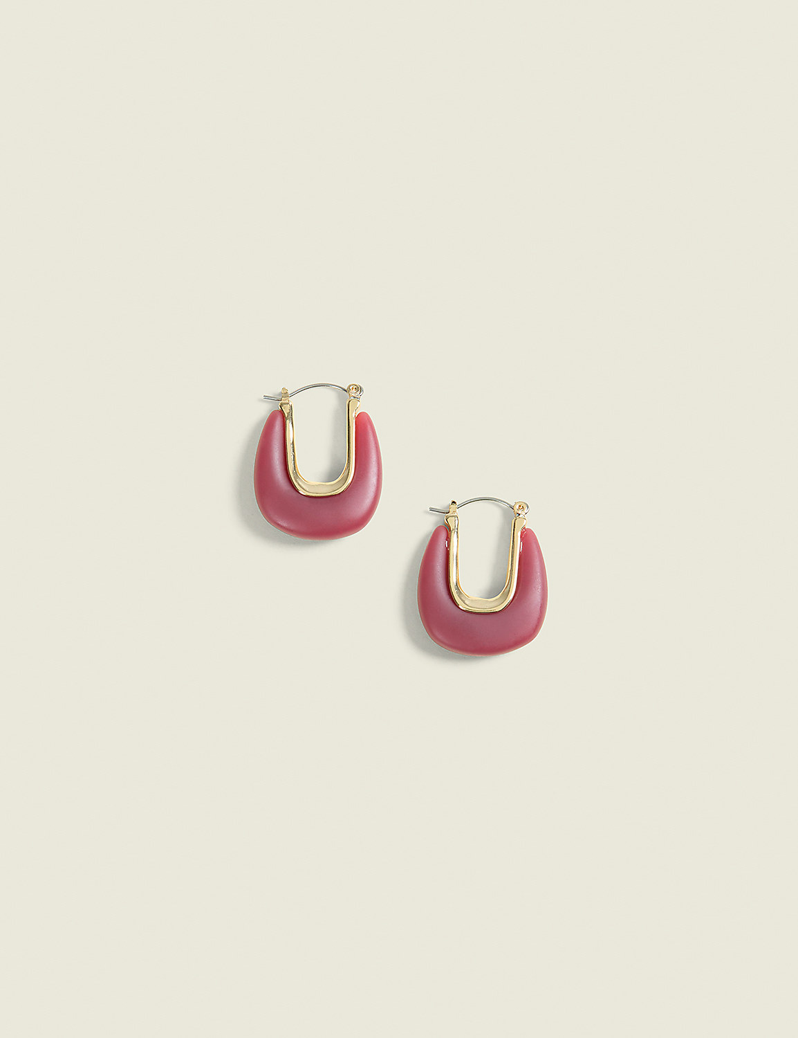 A pair of matte pink U-shaped earrings with gold accents rests on a pale yellow background. Product Image 1
