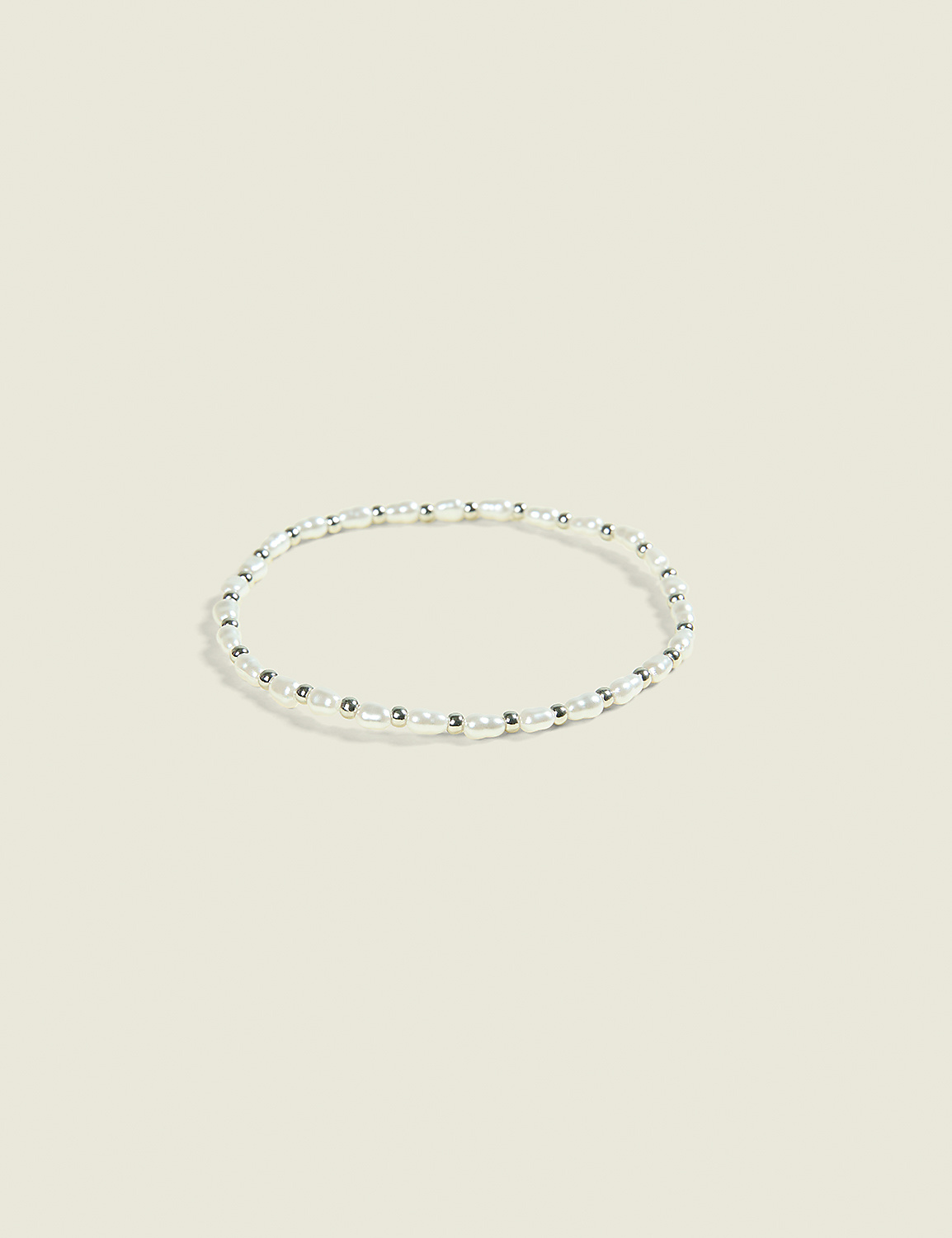 A delicate pearl and silver bead bracelet rests on a soft, pale background. Product Image 1