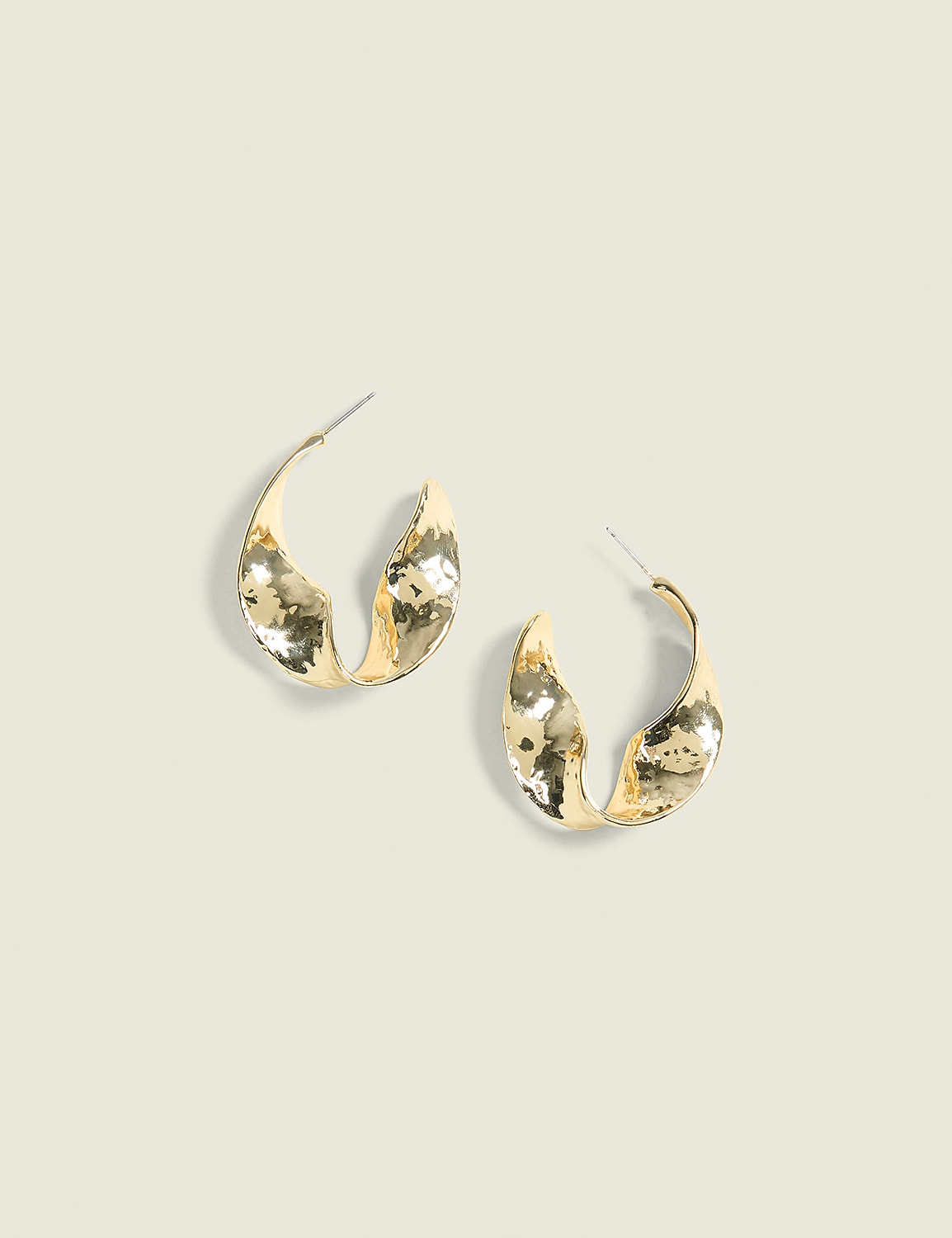 A pair of textured gold hoop earrings rests on a light beige background. Product Image 1