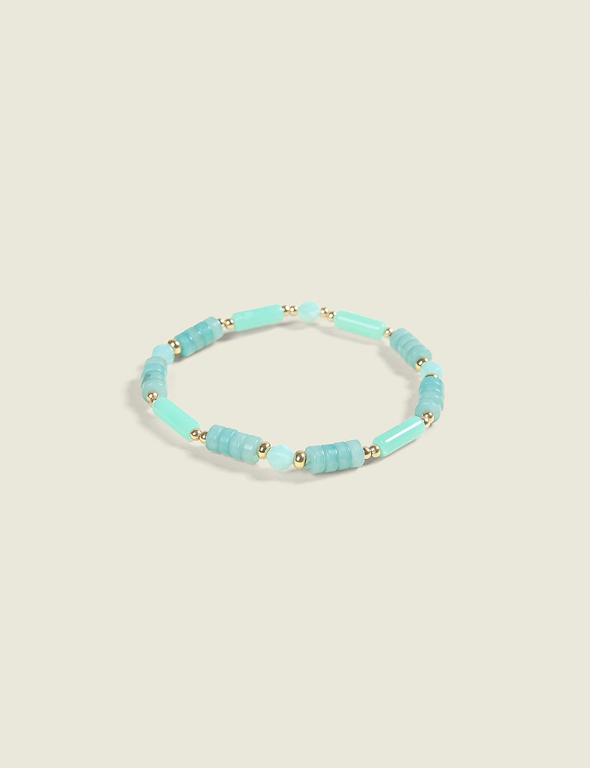 A light blue and green beaded bracelet with gold accents rests on a pale cream background. Product Image 1