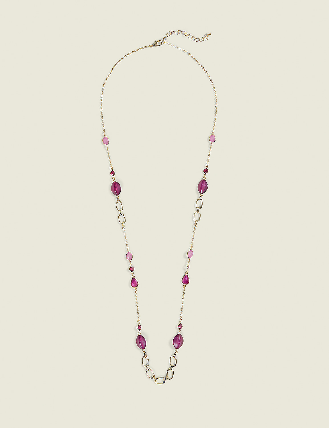 A long, gold-toned necklace with various shades of pink and purple beads and oval links is laid out against a plain, light beige background. Product Image 1