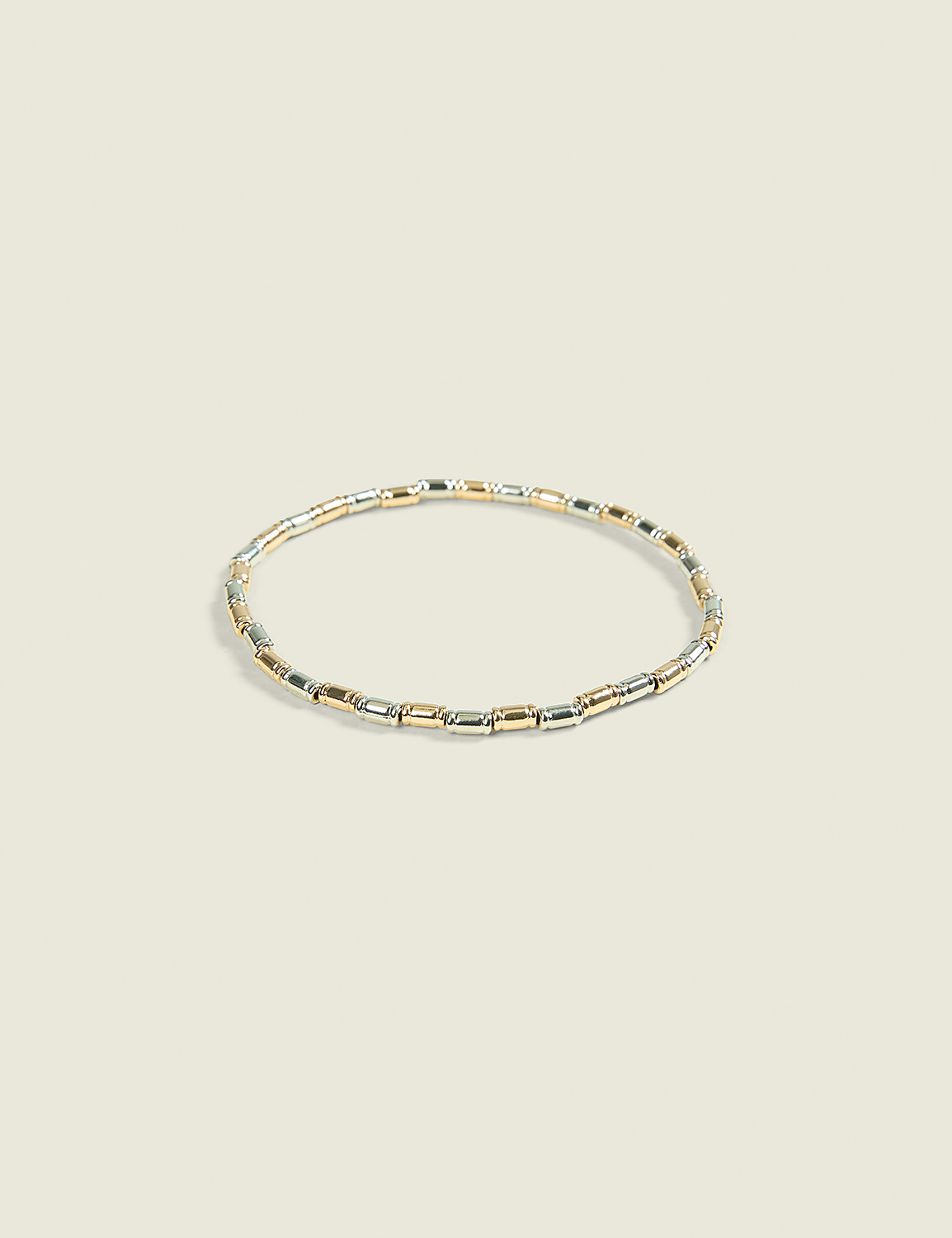 A delicate bracelet with alternating gold and silver rectangular beads rests on a soft, pale background. Product Image 1