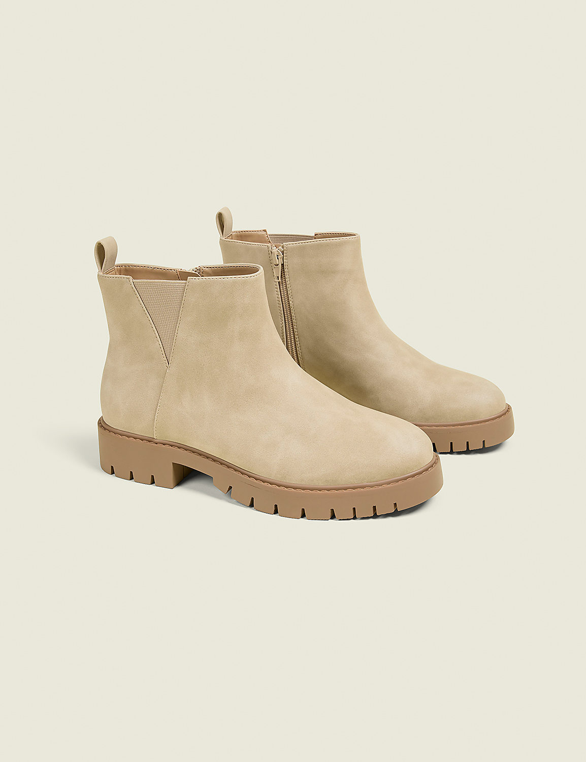 A pair of beige suede Chelsea boots with thick tan soles are displayed against a plain, light beige background. Product Image 1