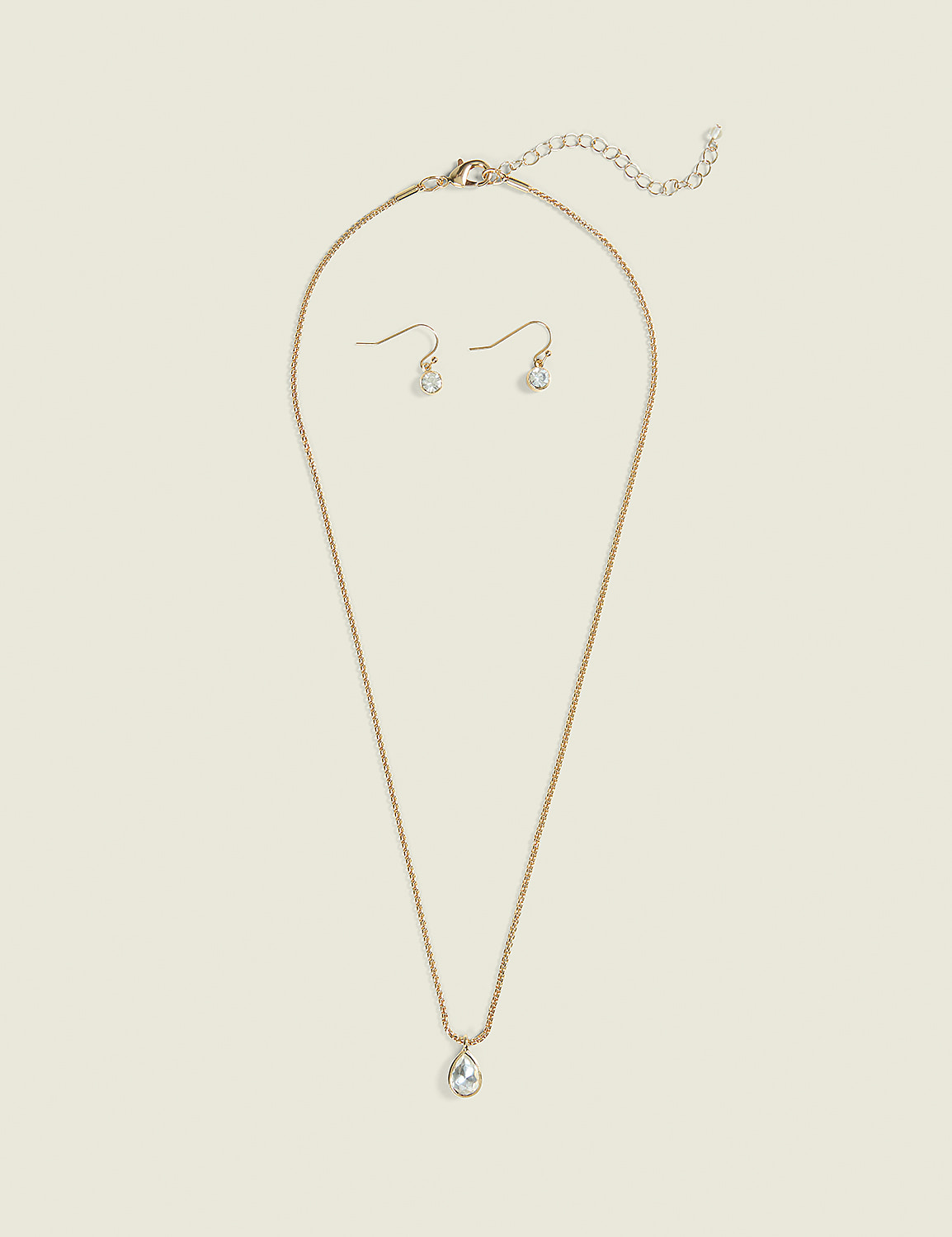 A delicate gold necklace with a teardrop pendant and matching earrings rest on a plain, light beige background. Product Image 1
