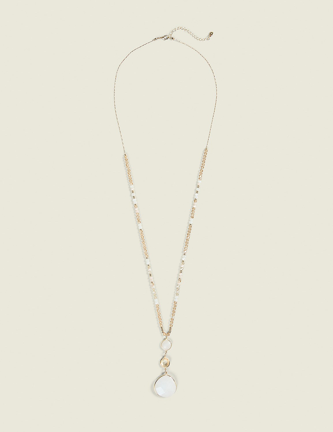 A long, delicate gold necklace with pearl and crystal beads hangs against a plain, light beige background. Product Image 1