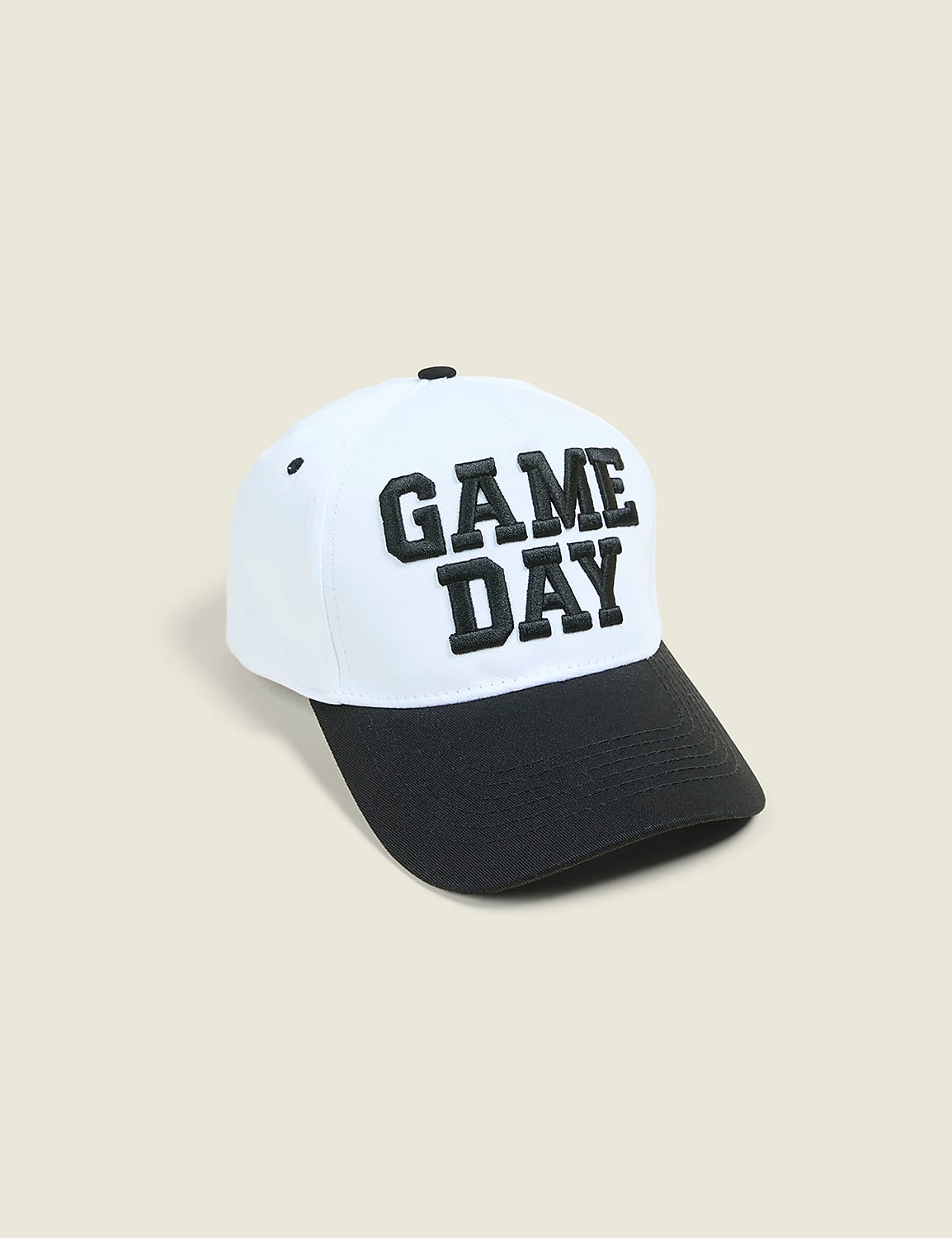 A white baseball cap with "GAME DAY" embroidered in black is displayed against a plain, light beige background. Product Image 1