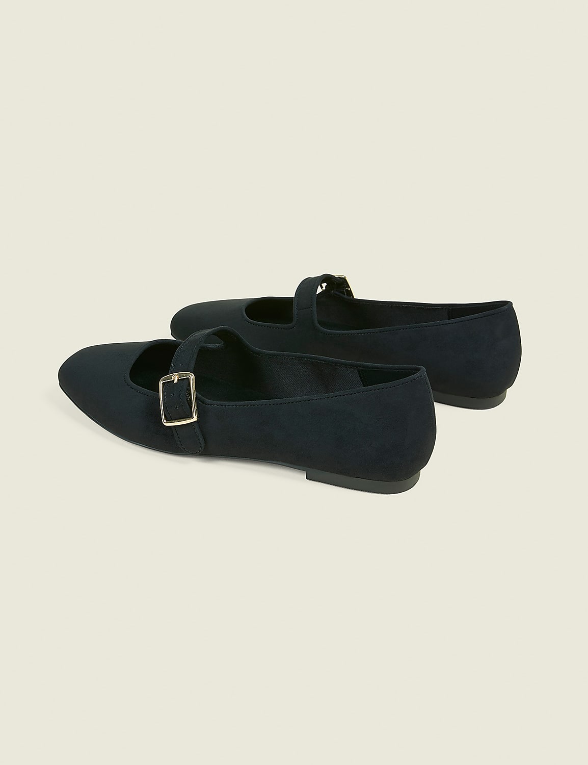 A pair of black Mary Jane flats with gold buckles rests on a plain, light-colored background. Product Image 2