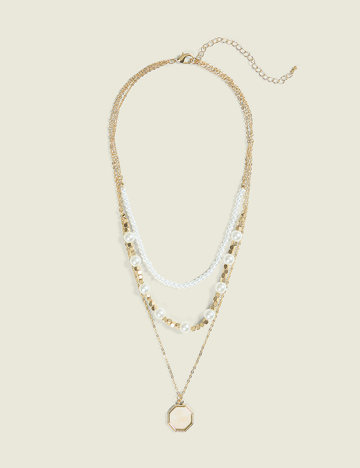 A layered gold necklace with pearls and a locket pendant rests against a plain, light-colored background. Product Image 1