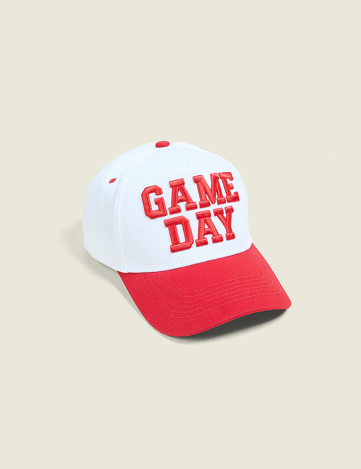 A white baseball cap with a red brim and "GAME DAY" embroidered in red sits on a light beige background. Product Image 1