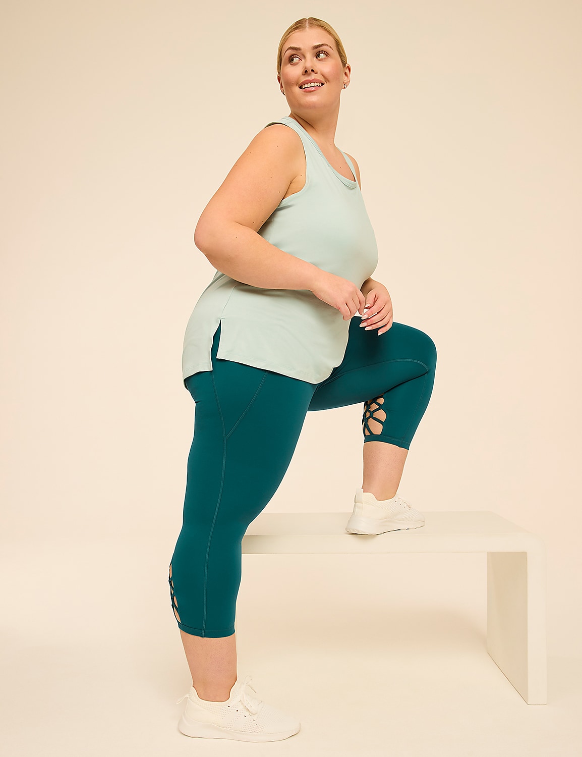 A woman in teal athletic wear steps onto a white bench against a plain cream background. Product Image 3