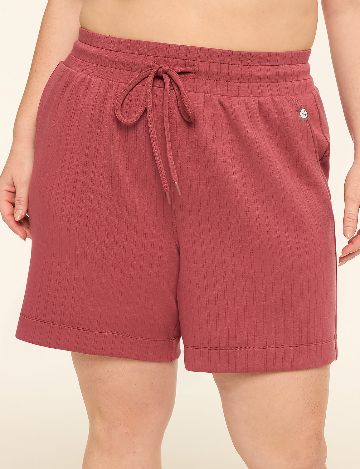 A person wearing rose-colored ribbed shorts with a drawstring stands against a plain, light-colored background. Product Image 1