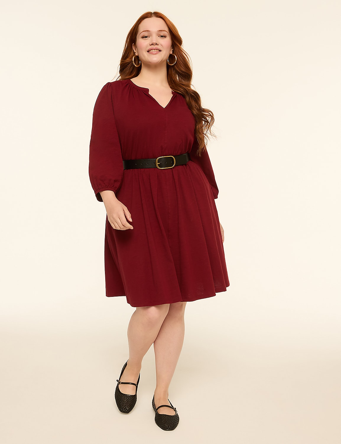 A woman in a burgundy dress and black flats stands against a plain, light-colored background. Product Image 1