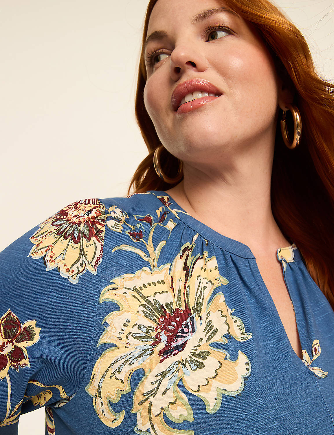 A woman with auburn hair and gold hoop earrings smiles as she looks to the side, her blue floral-print top filling the foreground against a plain background. Product Image 3