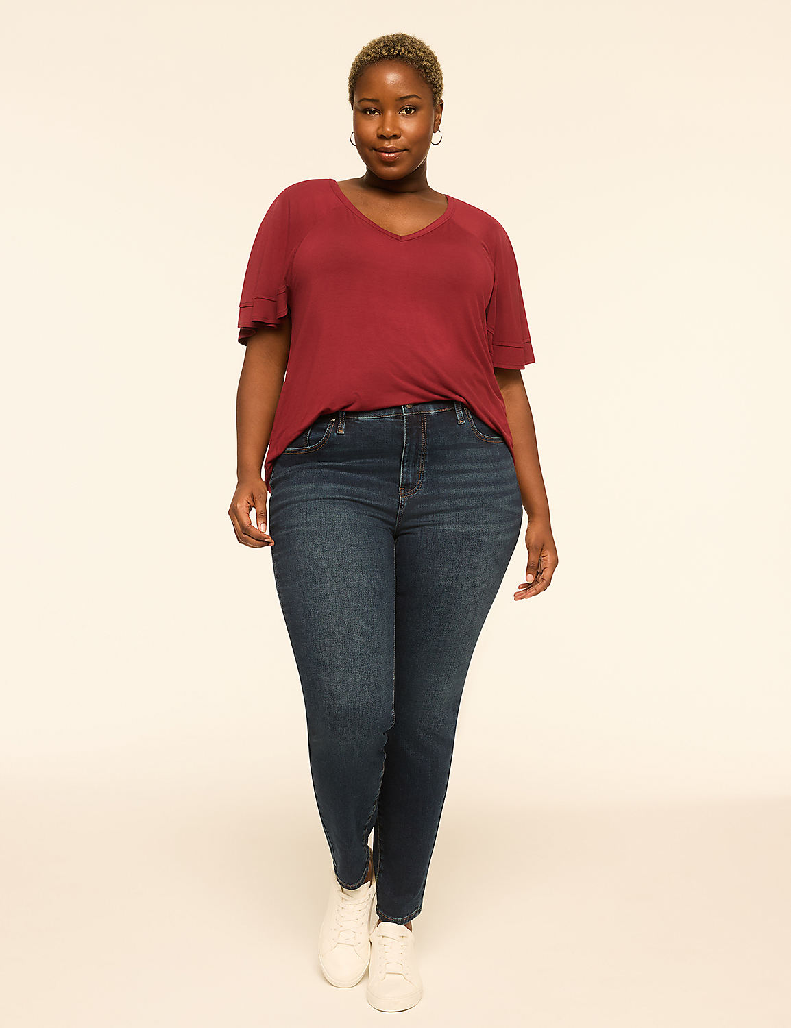 A woman in a maroon v-neck shirt and dark wash jeans stands against a plain, light-colored background. Product Image 3