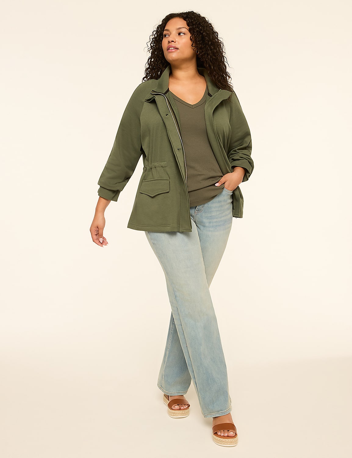 A woman in a green jacket and jeans walks against a plain, light-colored background. Product Image 3