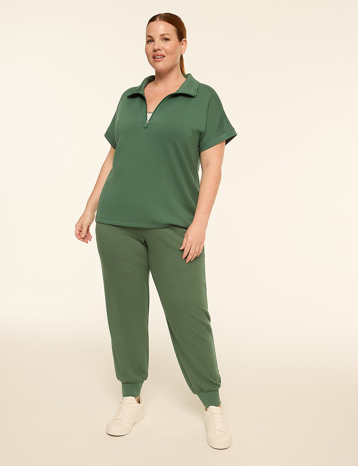 A woman in a green tracksuit stands against a plain, light-colored background. Product Image 3