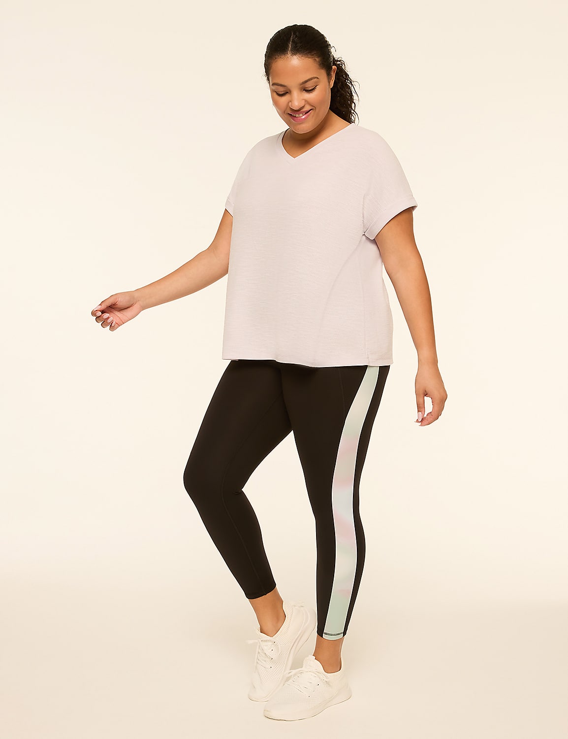 A woman in a light purple v-neck shirt and black leggings with a pastel stripe stands against a plain, light-colored background. Product Image 3