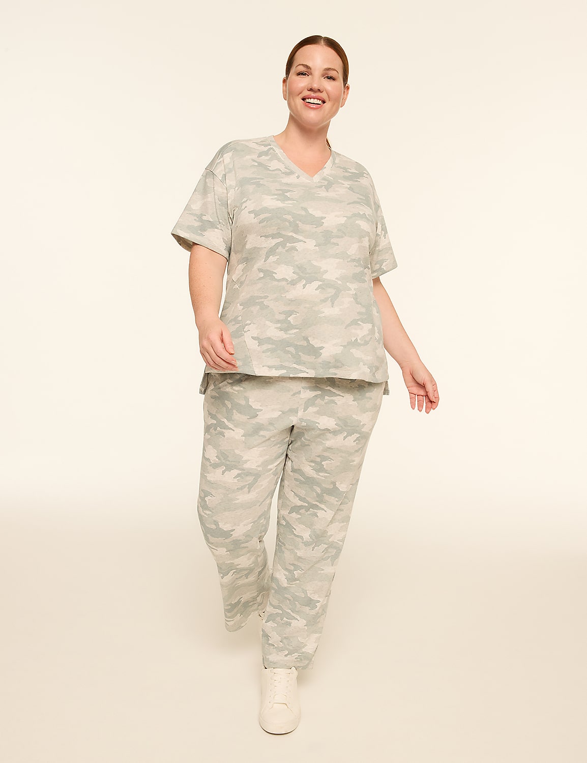A smiling woman in a camouflage loungewear set walks forward against a plain, light-colored background. Product Image 3