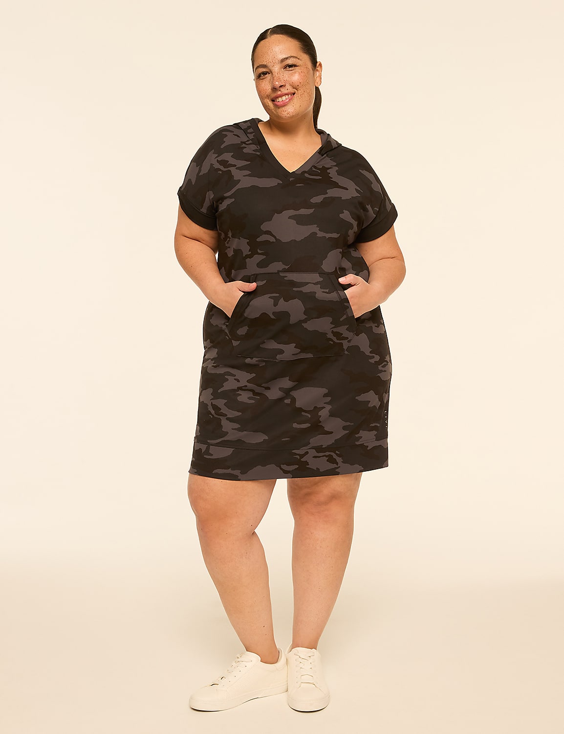 A woman in a camouflage hoodie dress and white sneakers stands against a plain, light-colored background. Product Image 1