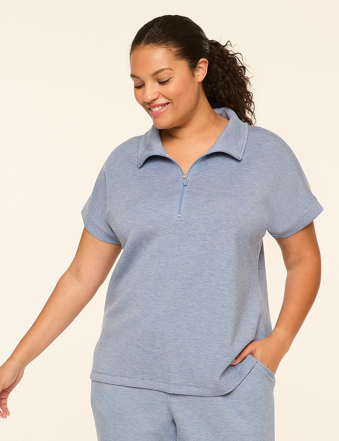 A smiling woman in a light blue zip-neck top and matching pants stands against a plain, light background. Product Image 1