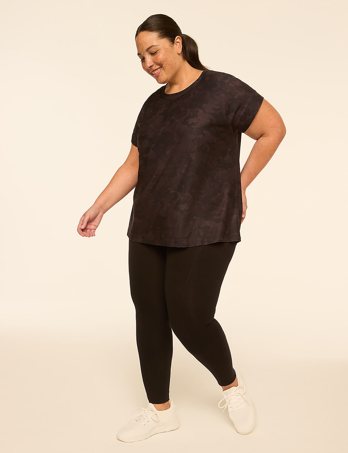 A woman in a dark tie-dye t-shirt and black leggings stands against a plain, light-colored background. Product Image 3