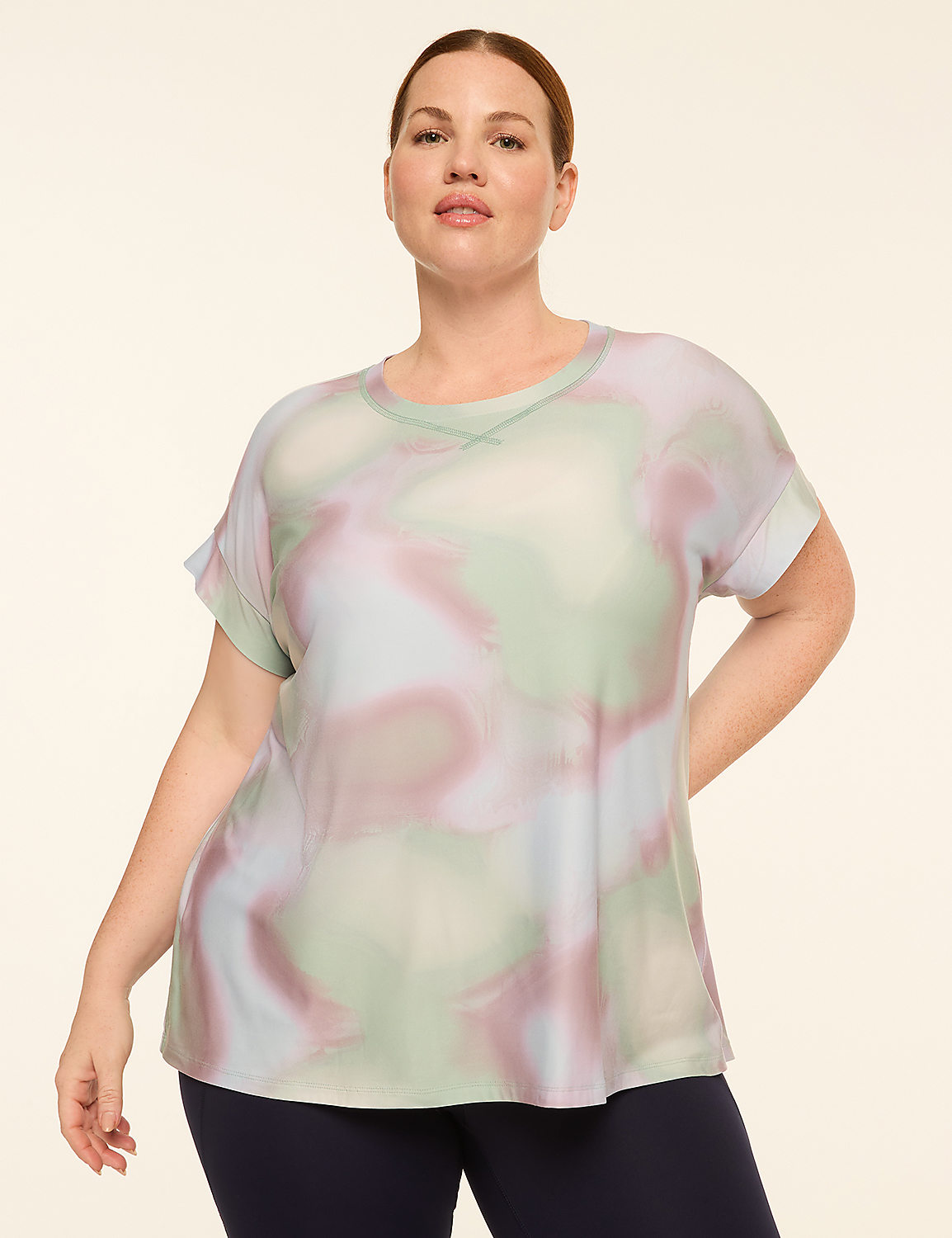 A woman in a tie-dye t-shirt and dark leggings stands against a plain, light-colored background. Product Image 1