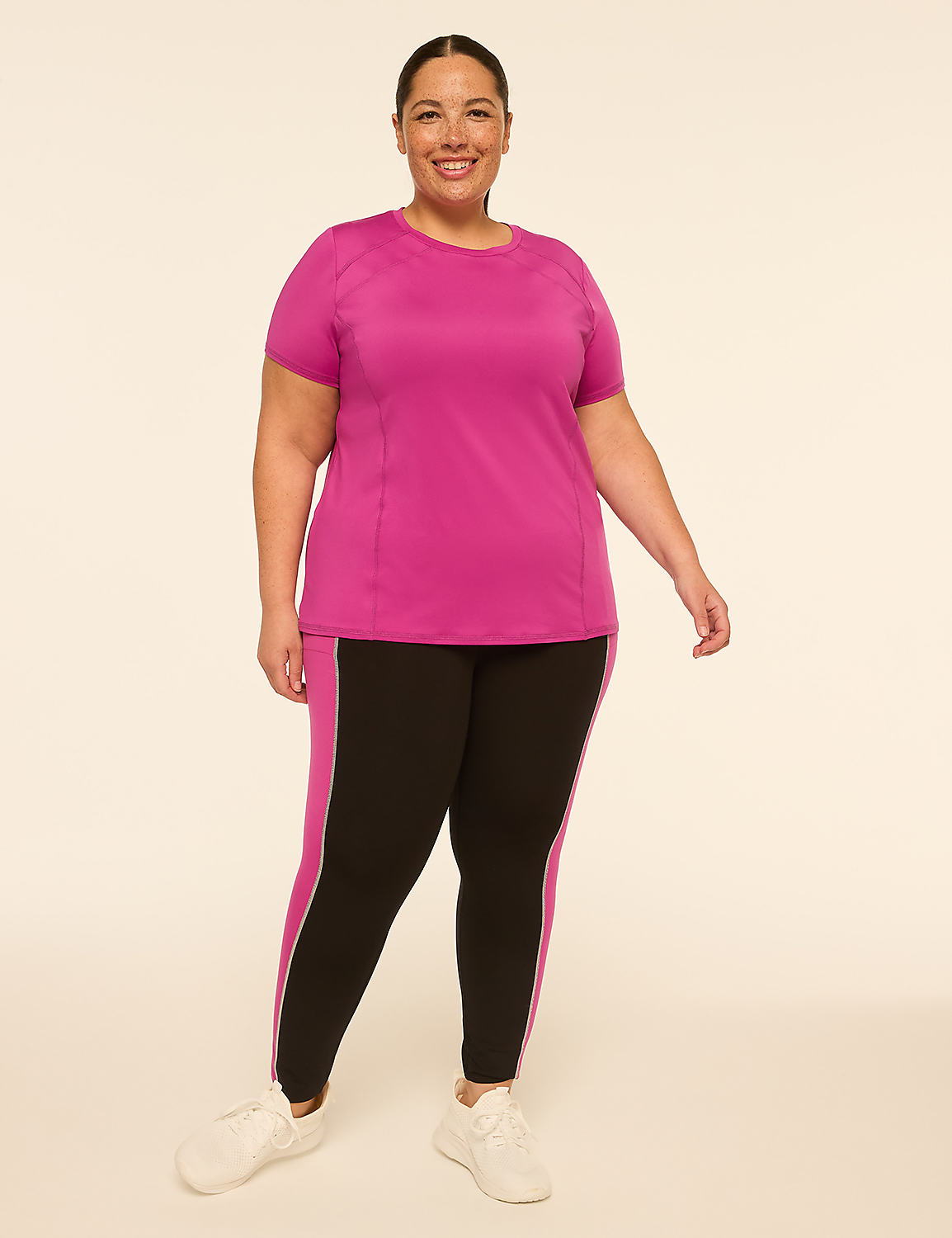 A smiling woman in a pink t-shirt and black leggings stands against a plain, light-colored background. Product Image 3