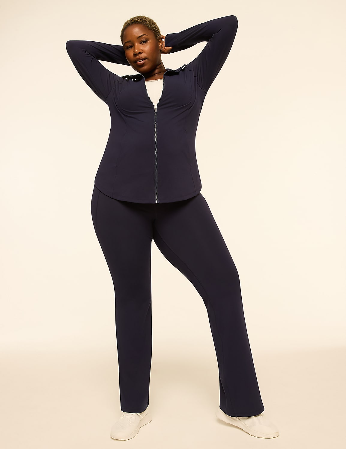 A woman in a navy tracksuit poses with her hands behind her head against a plain, light-colored background. Product Image 3