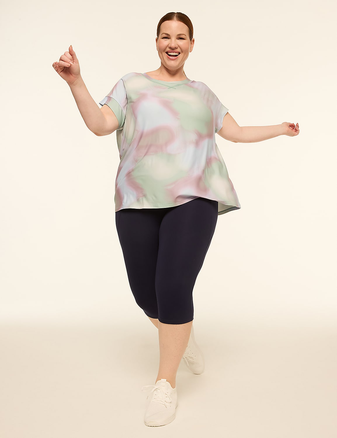 A smiling woman in a tie-dye top and navy capris poses against a plain, light-colored background. Product Image 3