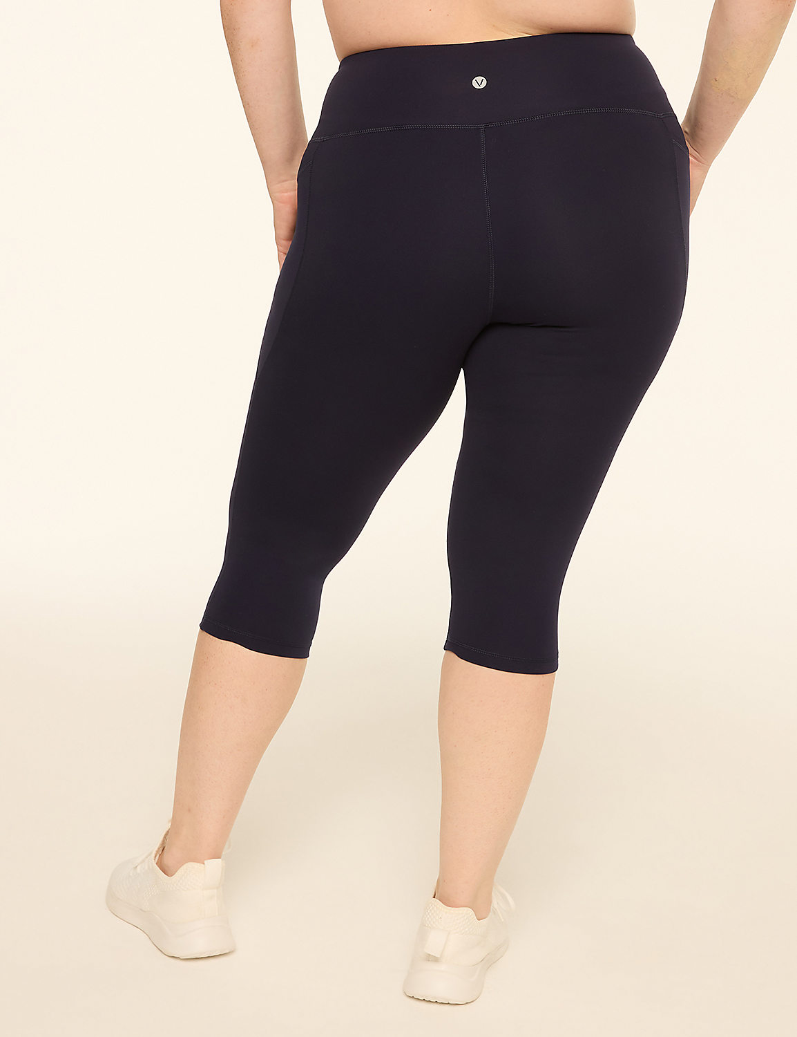 A person wearing navy blue capri leggings and white sneakers stands against a plain cream background. Product Image 2