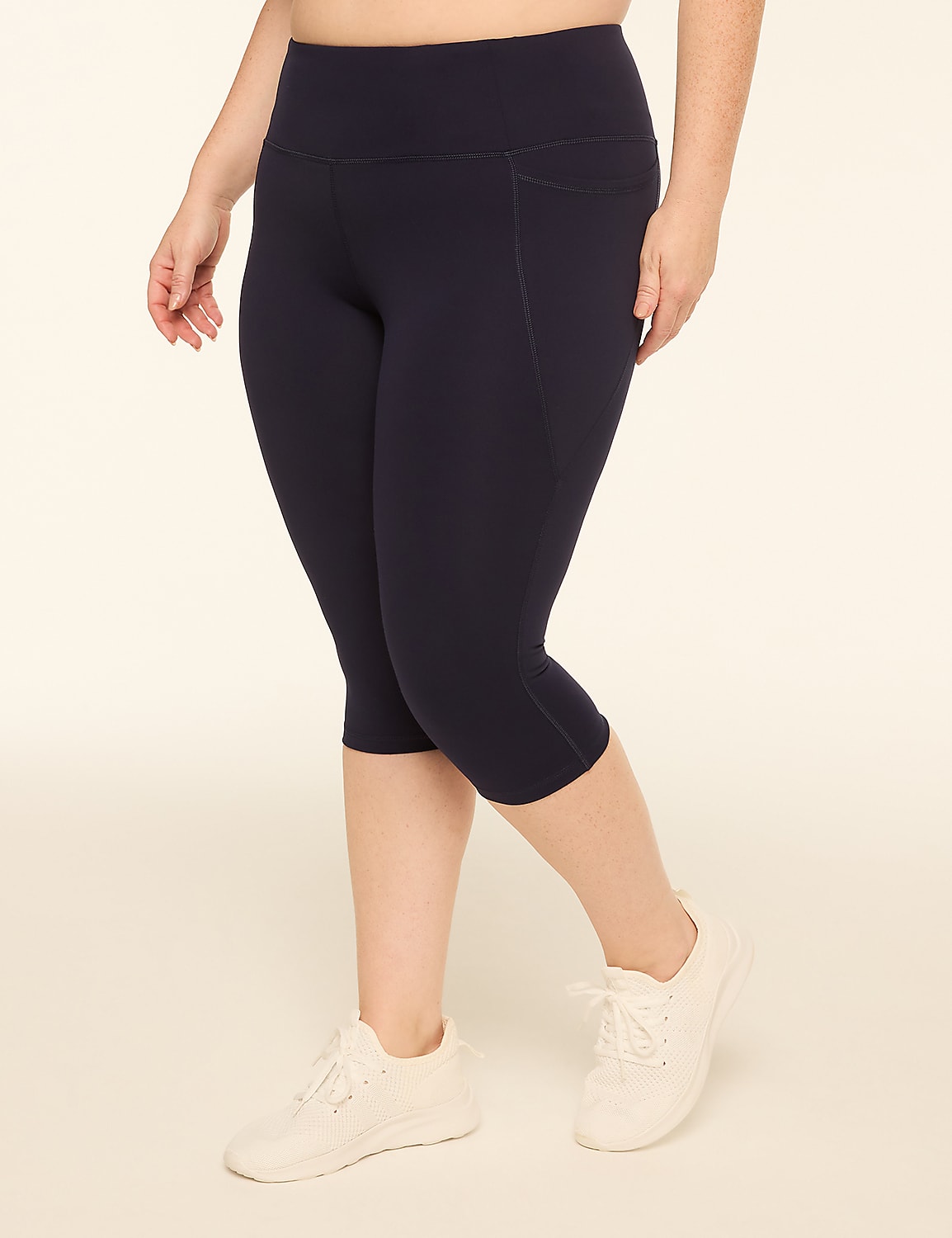 A woman in navy capri leggings and white sneakers stands against a plain, light-colored background. Product Image 1