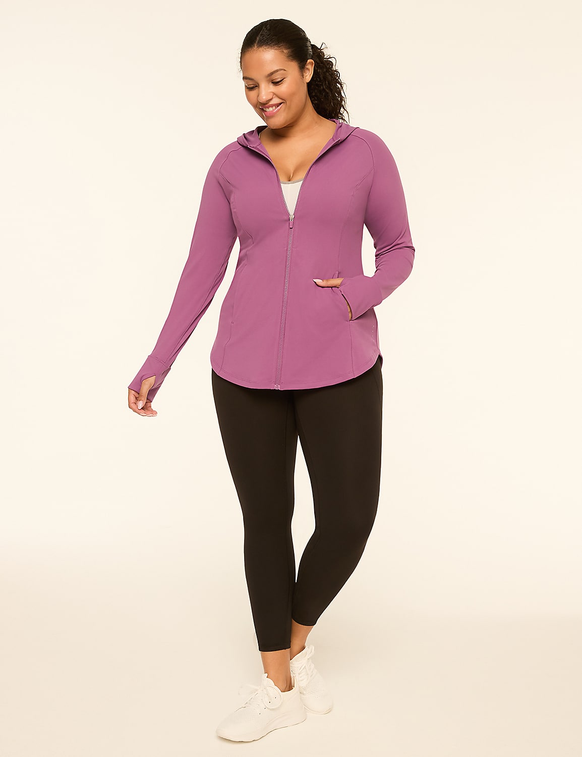 A woman in a purple zip-up hoodie and black leggings stands against a plain, light-colored background. Product Image 3